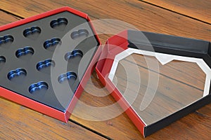 Gift box. Empty heart-shaped paper box in black plastic with aged wooden base, red and black box,