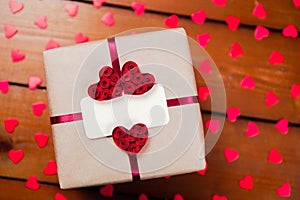Gift box with empty tag and red ribbon and red hearts. Top view