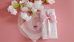 Gift box, envelope and apple tree branch on a pink background.