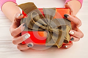 Gift box in female manicured hands.
