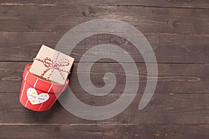 Gift box and flower pot are on the wooden background with empty