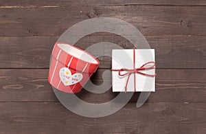 Gift box and flower pot are on the wooden background with empty