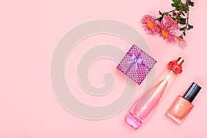 Gift box, flowers, bottle of perfume and bottle with nail polish on a pink background. Women cosmetics and accessories.