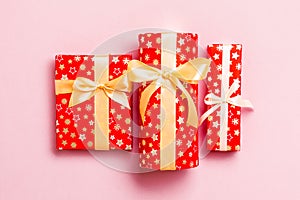 Gift box with gold bow for Christmas or New Year day on pink background, top view