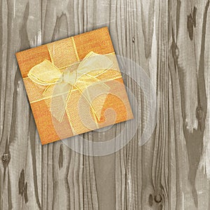 Gift box with gold ribbon with bow on Vintage wooden background