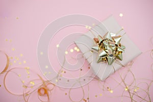 Gift box with golden bow on black background with decoration and sparkles. Festive concept copyspace top horizontal view