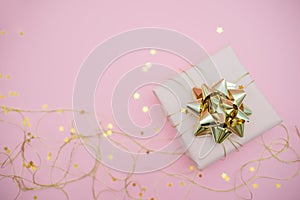Gift box with golden bow on black background with decoration and sparkles. Festive concept copyspace top horizontal view