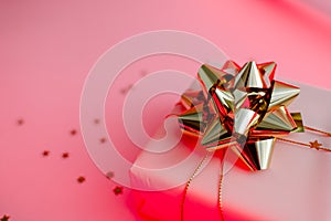 Gift box with golden bow on black background with decoration and sparkles. Festive concept copyspace top horizontal view