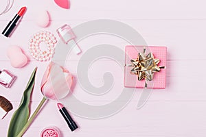 Gift box with golden bow near makeup products