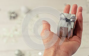 Gift box in hand on a gray light background for congratulations