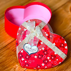 Gift box with heart shape with inscription i love you on wooden background