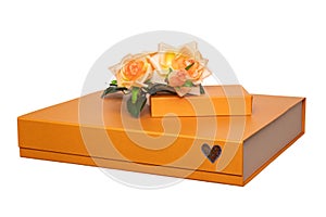 Gift box isolated. Close-up of a big and a small golden gift box with a bouquet of beautiful orange roses on it isolated on a