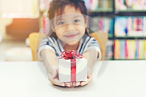 Gift box for kids girl. White box with red bow in the girl hands for give a gift