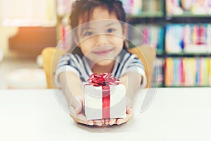 Gift box for kids girl. White box with red bow in the girl hands for give a gift photo