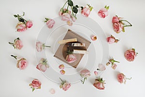 Gift box with natural homemade soap bars and rose flowers on white background. Holiday gift, opening present, top view.