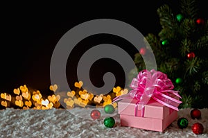 Gift box and ornaments with Christmas tree and love shape bokeh lights background.