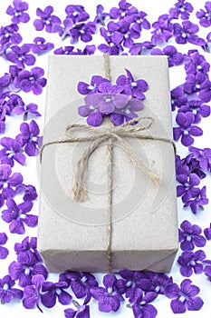 Gift box package wrapped with paper and rope with purple flowers