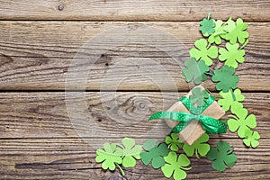 Gift box with paper clover leaves on the old wooden background.