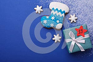 Gift box with paper tag, gingerbread cookies and space for text on blue background, flat lay. December, 19 - Saint Nicholas Day