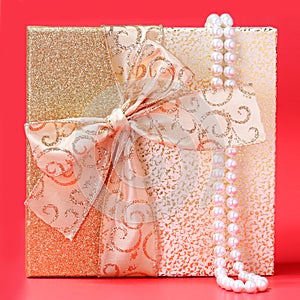 Gift Box with Pearl Necklace over red background. Christmas