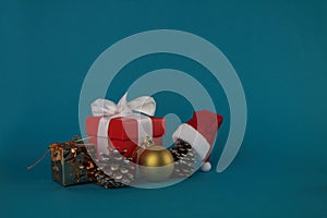 Gift box, pine cones, christmas ball and Santa hat isolated on blue background. Christmas concept