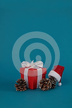 Gift box, pine cones and Santa hat isolated on blue background. Christmas concept