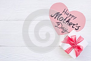 Gift box with pink ribbon over Happy Mothers day greeting card