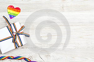 Gift box with rainbow LGBT ribbon on a light wooden background