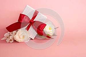 Gift box with red bow on a pink background . valentine `s or Mother`s or Women `s  day celebration concept