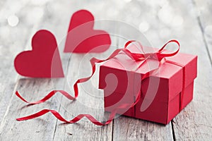 Gift box with red bow ribbon and two paper heart