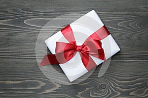 Gift box with red bow on wood table