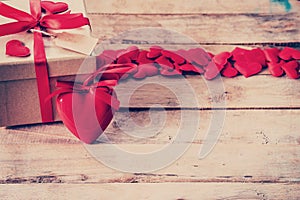 Gift box and red heart on wood table with space