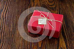 Gift box in red paper on old wooden background