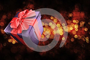 Gift box with red ribbon on golden bokeh background. 3d