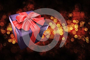 Gift box with red ribbon on golden bokeh background. 3d