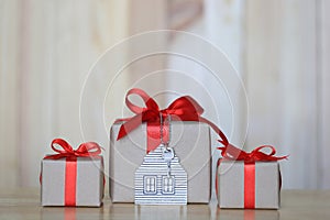 Gift box with red ribbon and house model with keys on wooder background, Gift new home and Real estate concept