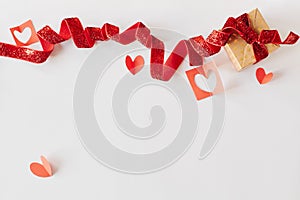 Gift box with red ribbon and red paper hearts on white background. Valentine`s day, love, holiday present concept