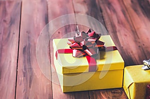 Gift box and red ribbon with tag on wood background with space