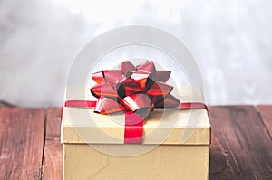 Gift box and red ribbon with tag on wood background with space