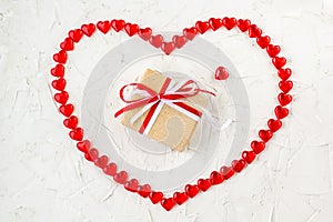 Gift box with red and white bow ribbon into heart of hearts on white table for Valentines day
