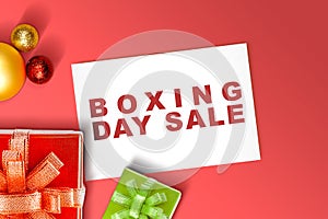Gift box with a ribbon and Christmas ornament with Boxing Day Sale text on paper