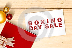 Gift box with a ribbon and Christmas ornament with Boxing Day Sale text on paper