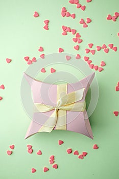 Gift box with ribbon on green pastel background with copy space. Minimal cincept of holiday. Top view, spring background.