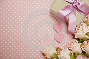 Gift box with roses bouquet with space copy on pink polka dot background