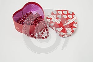 Gift box in the shape of a heart with red beads on a white background. Valentine`s Day. women`s Day.new year