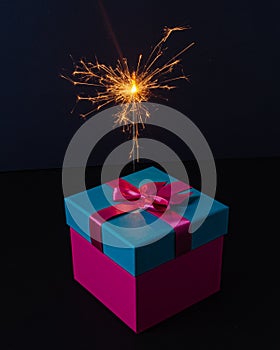 Gift box with a sparkler on dark background