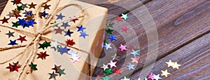 Gift box with star. Creative concept with festive decor on black background. Confetti stars, red, yellow with gift box. Explosion