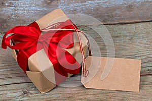 Gift box with tag with empty space for a text on wooden backg