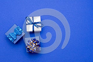 Gift box tied Blue satin ribbon bow on classic blue background, copy space. greeting card . birthday, father`s day, christmas