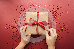 Gift box tied with red ribbon on pastel pink background